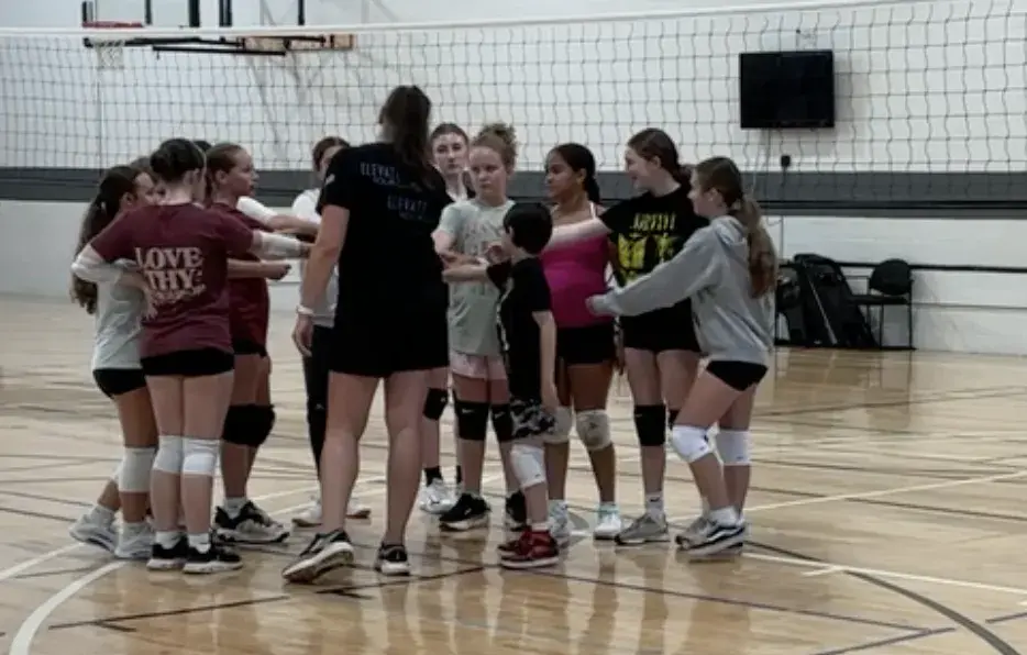 Coach Lisa huddled up with young volleyball players in Fuquay-Varina, NC